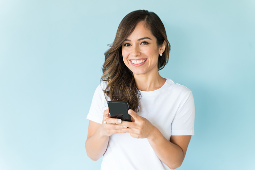 Beautiful smiling woman using smartphone over colored background
