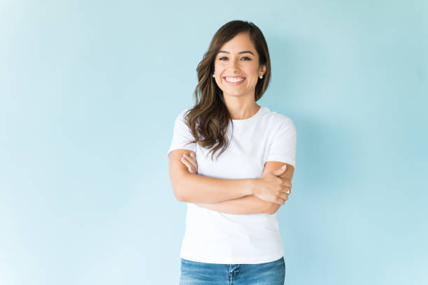 Confident Woman Over Isolated Background Portrait of good looking female model standing with arms crossed against blue background arms crossed stock pictures, royalty-free photos & images