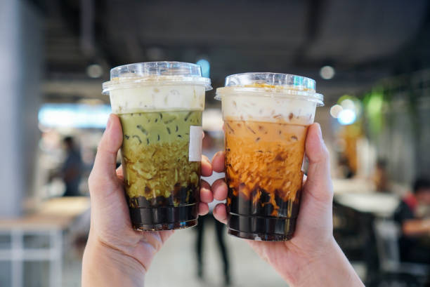 Matcha Green tea and Thai Tea Bubble drinks. Man holding a plastic cup of bubble/boba matcha green tea and Thai tea with brown sugar and topped with cheese cream. bubble tea photos stock pictures, royalty-free photos & images