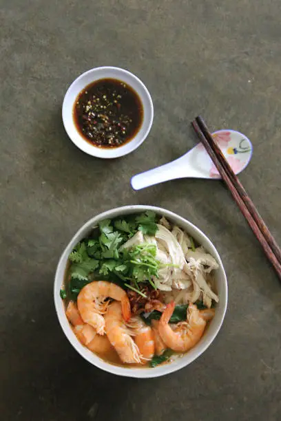 Photo of Shredded chicken, savoury broth, and prawn chili oil paired with Ipoh's signature kway teow noodle make up the delicious bowl of noodles in Ipoh, Malaysia.