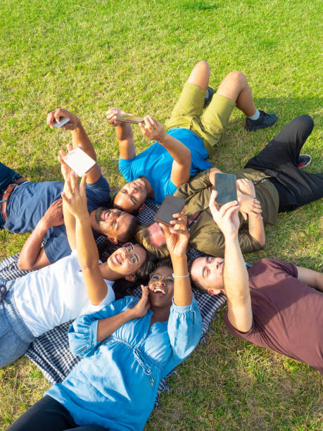 istock Happy friends lying on grass with smartphones 1166754260