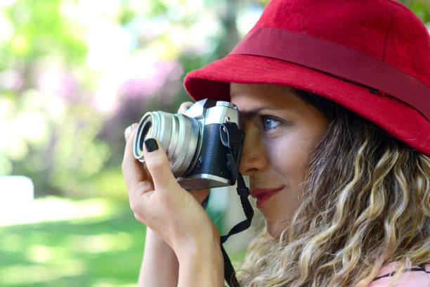 portrait of young woman having fun taking photos with retro film camera. Outdoor lifestyle portrait.