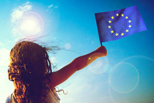 Little girl waving European union flag on sunny beautiful day