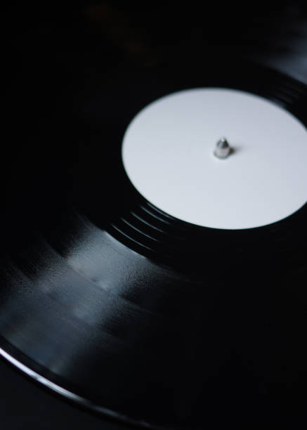 istock Grooves on vinyl record disc with white label spinning on turntable 1166757613