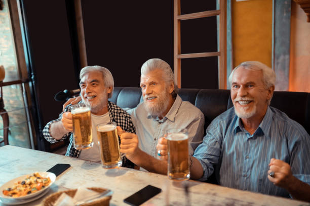 istock Beaming pensioners drinking beer and watching football 1166760604