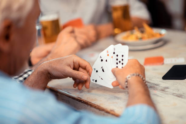 istock Grey-haired mature man wearing bracelet holding cards 1166760704