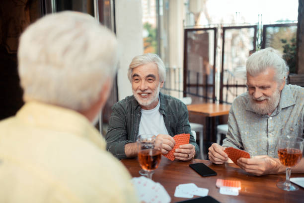 istock Aged bearded man laughing while playing cards with friends 1166760998