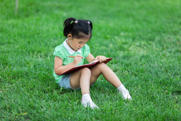 istock Cute little girl learning on the lawn 1166761229