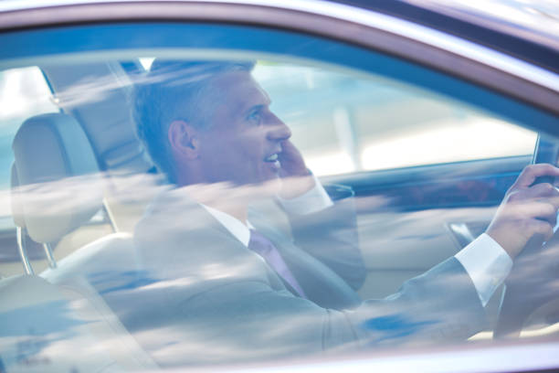 istock Mature businessman talking on mobile phone while driving car 1166763610