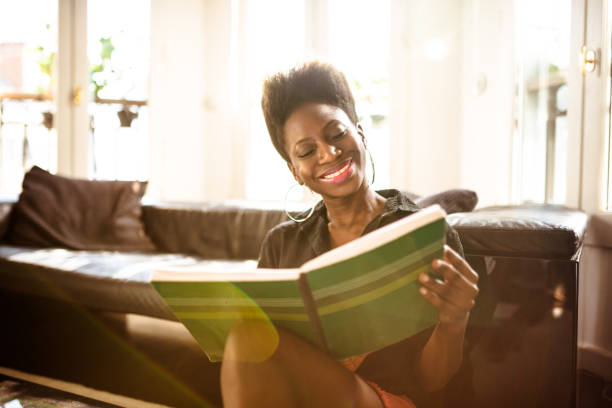 istock afro woman reading a book at home 1166763645