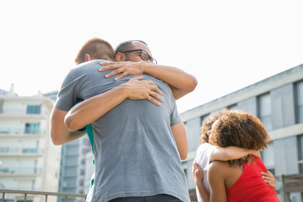 Happy men in casual embracing each other. Close friends meeting on outdoor building terrace, hugging and greeting each other. Affection concept