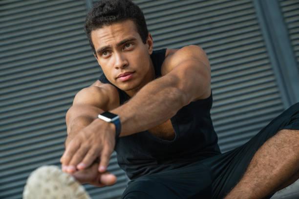 istock Confident young man stretching his body before running while sitting outdoors 1166768092