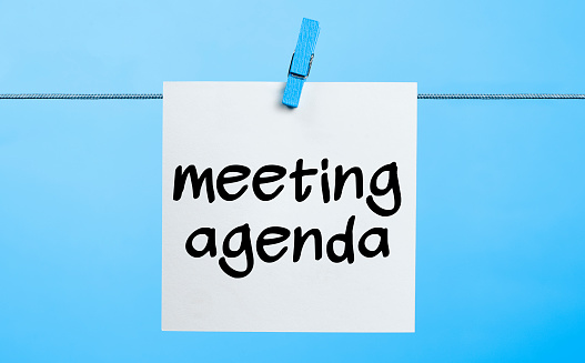 Meeting agenda Written On White Paper Hanging On Blue Background With the Latch