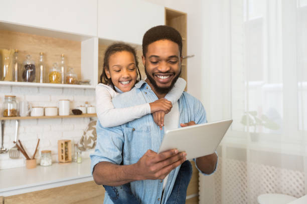 istock Father and daughter having video call on tablet in kitchen 1166771956