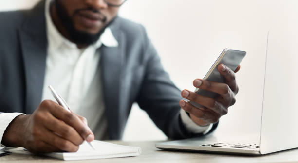 istock African American businessman looking at smartphone taking notes in office 1166772043