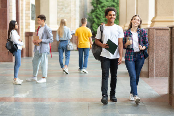 istock Happy college classmates walking in campus during break 1166773691