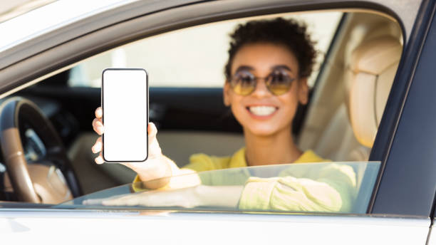 istock Happy afro woman in auto showing smartphone with blank screen 1166773697