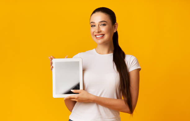 istock Cladful Lady Showing Digital Tablet Screen Over Yellow Background 1166773828