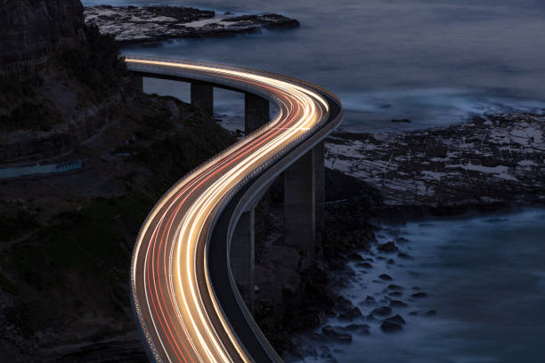 Traffic on Bridge Car light trails on Sea Cliff Bridge, a balanced cantilever bridge located south of Sydney, New South Wales, Australia sea bridge stock pictures, royalty-free photos & images
