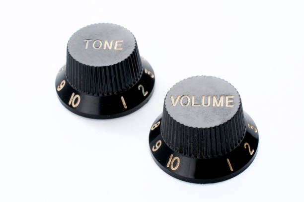 Vintage black guitar volume and tone knobs on white background