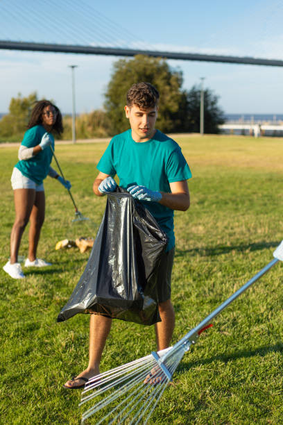 istock Volunteers in uniforms removing trash from grass 1166777440
