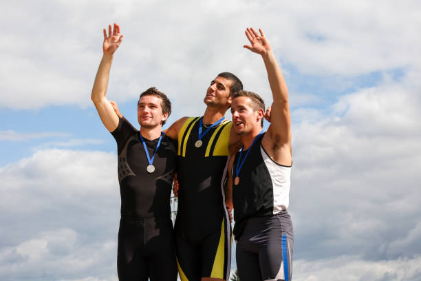 Three men with gold, silver and bronze medal standing on podium and waiting for flowers.