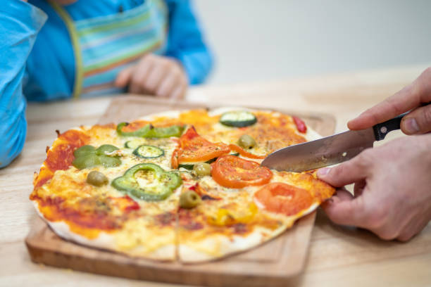 istock Woman slicing pizza 1166780642
