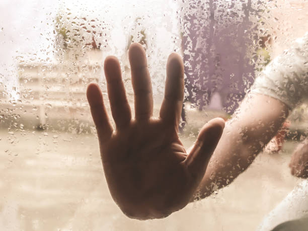 istock Human Hand pressed against a window with Drops Of Rain on it. 1166786611