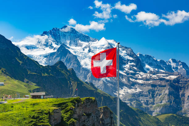 Mannlichen viewpoint, Switzerland Swiss flag waving and tourists admire the peaks of Jungfrau mountain on a Mannlichen viewpoint, Bernese Oberland Switzerland switzerland stock pictures, royalty-free photos & images