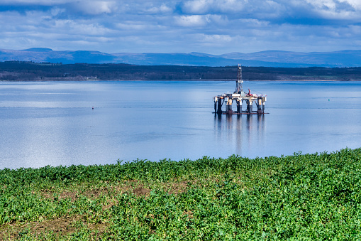Cromarty Firth, Scottish Highlands, UK - April 2, 2019:  One offshore oil platform sits in the Cromarty Firth, Scottish Highlands, UK.  These are drilling rigs used for the oil industry.  They extract fossil fuel and natural gas.