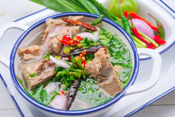 Spicy pork bone soup in Thai style Is a clear pork bone soup with large pork bones, decorated with chili and Thai herbs stock photo