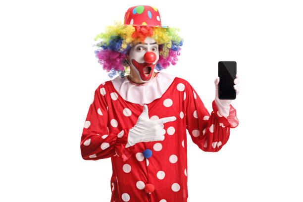 веселый клоун, держащий мобильный телефон и указывающий на него - clown circus telephone humor стоковые фото и изображения