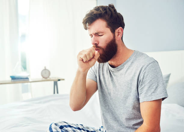 I'll have to get something for this cough Cropped shot of a young man coughing at home bronchitis stock pictures, royalty-free photos & images