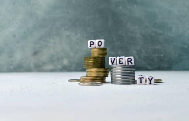 istock Poorness and lack of money concept with coins stack and poverty text on little cubes 1166805033