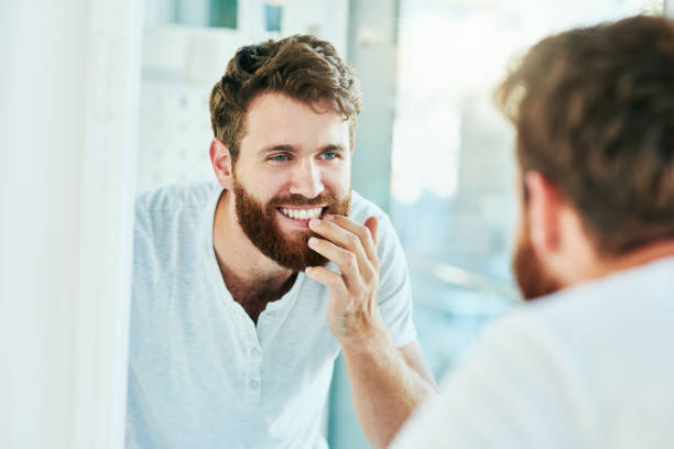 I've never seen a smile more perfect Cropped shot of a handsome young man looking at his teeth in the bathroom mirror dental health photos stock pictures, royalty-free photos & images