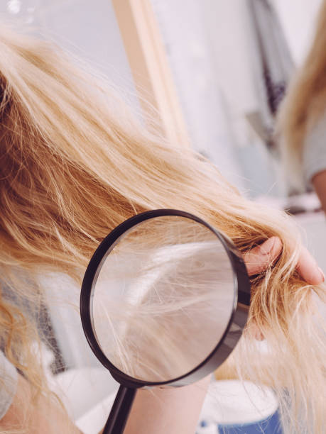 istock Woman looking at hair ends through magnifying glass 1166807265