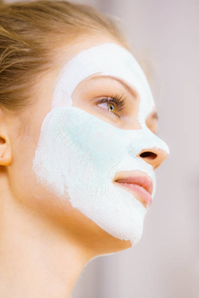 istock Girl with white green mud mask on face 1166807395