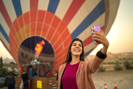 Young Woman Taking A Selfie With A Hot Balloon On Background