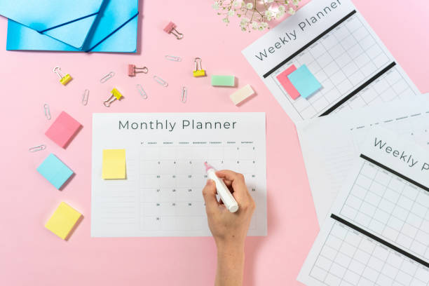 istock Woman writing at planner on pink pastel background 1166811375