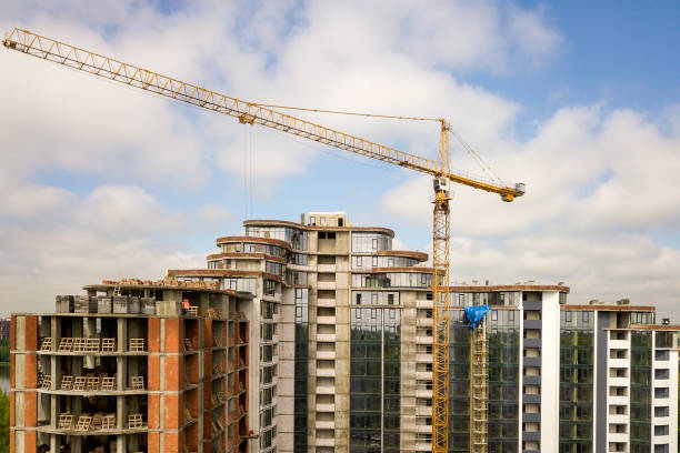 istock Apartment or office tall building under construction. Brick walls, glass windows, scaffolding and concrete support pillars. Tower crane on bright blue sky copy space background. 1166811717