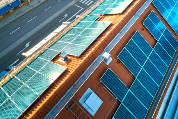 vue supérieure du système de panneaux voltaïques de photo solaire bleue sur le dessus de toit d'immeuble d'appartements. concept de production écologique renouvelable d'énergie verte. - voltaic photos et images de collection