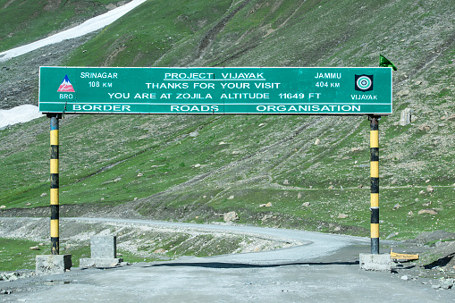 Kargil, India - July 07, 2015: Roadsign at the beginning of the Zoji La road in Kargil district of Ladakh, next to Dras village (at an altitute fo 3.280 m) which is reported to be the coldest inhabited place in India and the second coldest inhabited place in the world.This road, also called Indian National Highway, crosses seveal high mountain passes, the most well known are Fatu La (4.100 m) and Zoji La (3.528 m altitude).