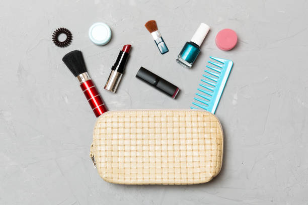 top view of set of make up and skin care products spilling out of cosmetics bag on cement background. beauty concept - pampering nail polish make up spilling imagens e fotografias de stock