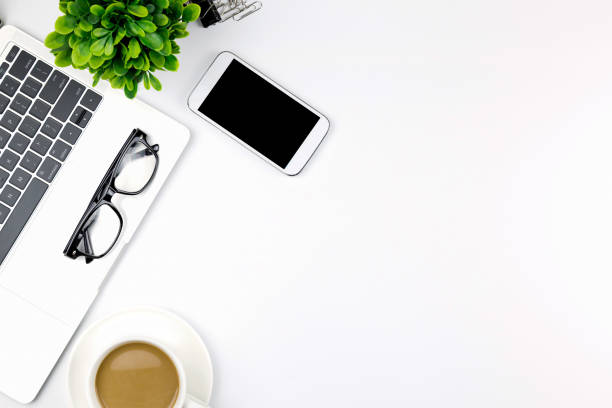 istock Modern white office desk table with laptop computer, smartphone with black screen over a notebook and cup of coffee. 1166814320