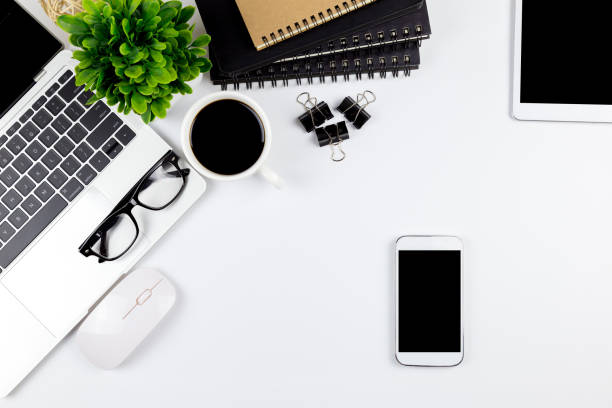 istock Modern white office desk table with laptop computer, smartphone with black screen over a notebook and cup of coffee. 1166816109