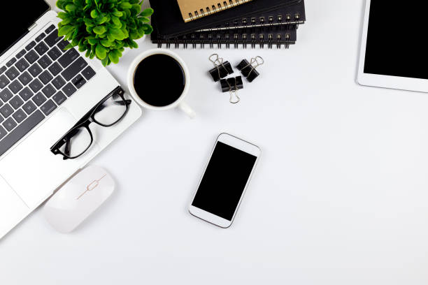 istock Modern white office desk table with laptop computer, smartphone with black screen over a notebook and cup of coffee. 1166816115