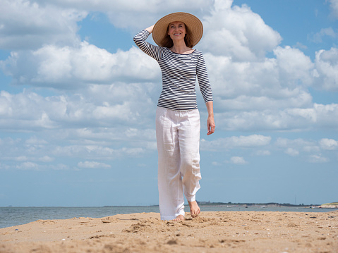 Carefree mature woman walking barefoot at beach