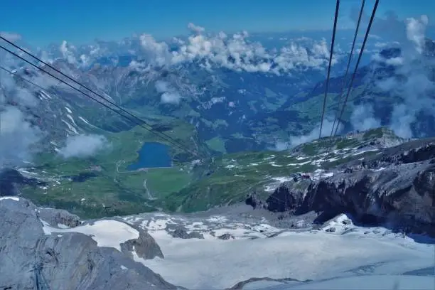 A spectacular series of 3 panoramic images of the high peaks of central Switzerland on an especially clear day in summer 2019. They are taken from the high altitude Cable-way "Titlis" that links Engelberg to Trüebsee and ultimately on to the permanent snow-ski slopes of Mount Titlis. The sheer expanse and grandeur of this unique landscape is perfectly captured with visibility on that day of over 80 miles at an altitude of around 10,000 ft, you can see virtually the whole of Central Switzerland in one view, simply by being in the right place at the right time. These shots are all taken looking down from the cable car and one can see the edge of the snowline very clearly - the softer, less harsh green mountains and alpine pastures are far below. This third and final image in the series looks North East towards Lake Constance and the alps of Southern Germany; again the lake resort at Trüebsee is clearly visible below.