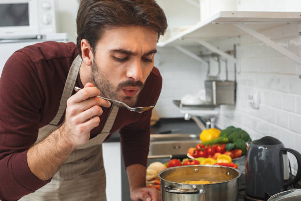 istock Young man cooking romantic dinner at home taste soup 1166824837