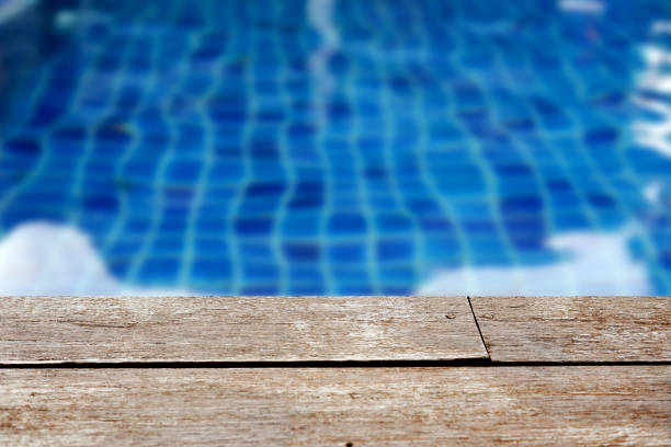 istock Empty rustic wooden table in front of blurred background of swimming pool. 1166824985